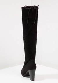 Stivale alto in suede nero sopra il ginocchio con tacco curvo, dettaglio in pizzo nella parte superiore e chiusura con zip sul lato.