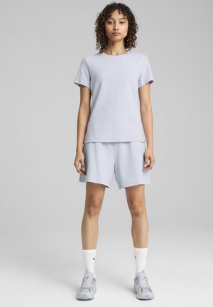 Lysblå kortærmet t-shirt og matchende shorts lavet af struktureret stof. Hvide sportsstrømper og grå sporty sko fuldender outfittet.