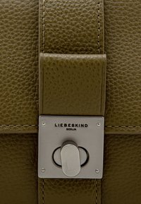 Borsa a tracolla in pelle verde oliva con finitura testurizzata, chiusura in metallo argentato e dettagli cuciti. Nome del marchio "LIEBESKIND BERLIN" esposto.