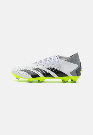Scarpa da calcio bianca e nera con tomaia perforata, suola giallo-verde e accenti grigi. Presenta lacci e una forma dinamica per le prestazioni.