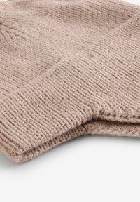 Bonnet en tricot rose clair avec un revers côtelé. Texture douce, légèrement pelucheuse, avec des mailles serrées dans une forme lisse et arrondie.