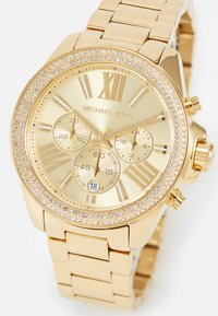 Goldfarbene Michael Kors Armbanduhr mit einem mit Kristallen besetzten Gehäuse, römischen Ziffern, drei Subdials und Datumsanzeige an einem Metallarmband.