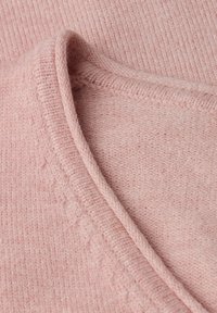 Suéter rosa claro con un acabado suave y texturizado. Presenta un cuello y un dobladillo acanalados, lo que realza su apariencia acogedora.