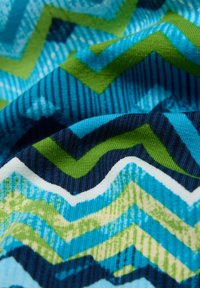 Stoff mit Chevron-Muster in Blau-, Grün- und Weißtönen, mit strukturierten Streifen und glattem, gewebtem Material.