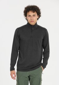 Schwarzer Langarm-Zip-Up-Pullover mit hohem Kragen, leichtem Stoff und subtilen Texturdetails. Kombiniert mit grünen Cargo-Hosen.