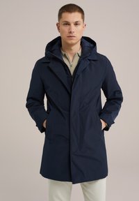 Abrigo impermeable azul marino con capucha, que cuenta con un cierre frontal, dos bolsillos laterales y un corte recto. Textura suave, diseño minimalista.