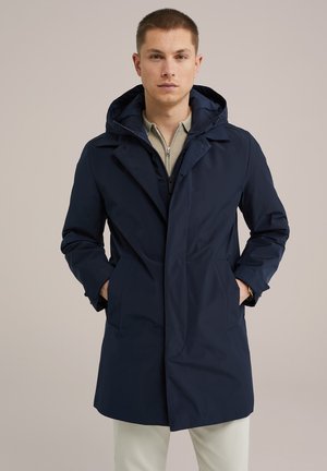 Abrigo impermeable azul marino con capucha, que cuenta con un cierre frontal, dos bolsillos laterales y un corte recto. Textura suave, diseño minimalista.