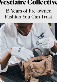 Personne portant des gants blancs inspecte un sac à main en cuir beige à l'aide d'une loupe sur une table de travail avec un tapis à quadrillage.