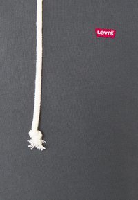 Felpa grigia con tessuto testurizzato, dotata di un laccio bianco e un'etichetta rossa del logo Levi's sul petto.