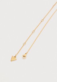 Κολιέ με αλυσίδα σε χρυσό τόνο, με τριγωνικό μενταγιόν που φέρει την εγχάρακτη επιγραφή "GUESS." Διαθέτει κούμπωμα με γαρίδα.