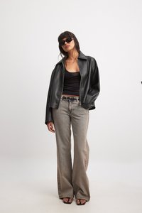 Melna mākslīgās ādas jaka, pieguļošs melns t-krekls, gaiši pelēki izsvītroti džinsi ar smalku rakstu un melnas sandales ar atvērtu purngalu.