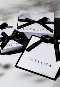 Drei weiße Geschenkkartons in unterschiedlichen Größen, mit schwarzem Band und "LATELITA"-Branding. Die Kartons verfügen über eine glatte Textur und eine scharfe rechteckige Form.