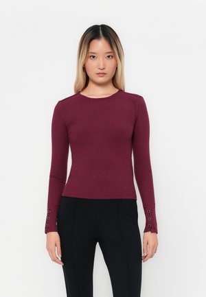 Haut à manches longues côtelé bordeaux avec un col rond et des accents boutonnés aux poignets, fabriqué dans un matériau extensible ajusté pour un fit près du corps.
