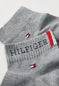 Graue Baumwollsocken mit gerippter Textur, gesticktem "HILFIGER"-Logo und einem kleinen mehrfarbigen Logo-Akzent nahe dem Bündchen.