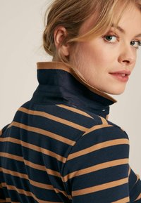 Marineblau und sandfarbener gestreifter Poloshirt mit hohem Kragen und gerippter Textur. Verfügt über eine schlanke Passform und sichtbare Nähte.