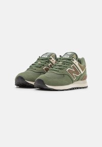 Zielone zamszowe i siateczkowe sneakersy z beżowymi akcentami, z czarną gumową podeszwą, okrągłym noskiem i sznurowanym zapięciem. Logo na bocznej ściance.