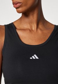 Czarny sportowy tank top wykonany z elastycznej tkaniny. Posiada okrągły dekolt oraz małe białe logo na klatce piersiowej.