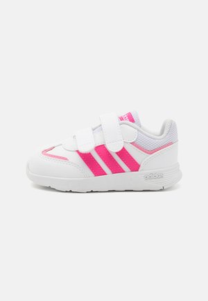 Scarpa sportiva bianca con dettagli rosa, dotata di due strap in Velcro, linguetta in rete testurizzata e tre strisce rosa sui lati.