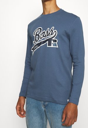 Camicetta blu a maniche lunghe in cotone, con il logo "Boss" in bianco con design a nastro. Vestibilità casual, scollatura rotonda e texture liscia.