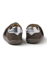 Zapatos de ante marrón con un tacón metálico plateado, diseño curvado y suelas flexibles. Presentan una superficie texturizada y detalles de costura.