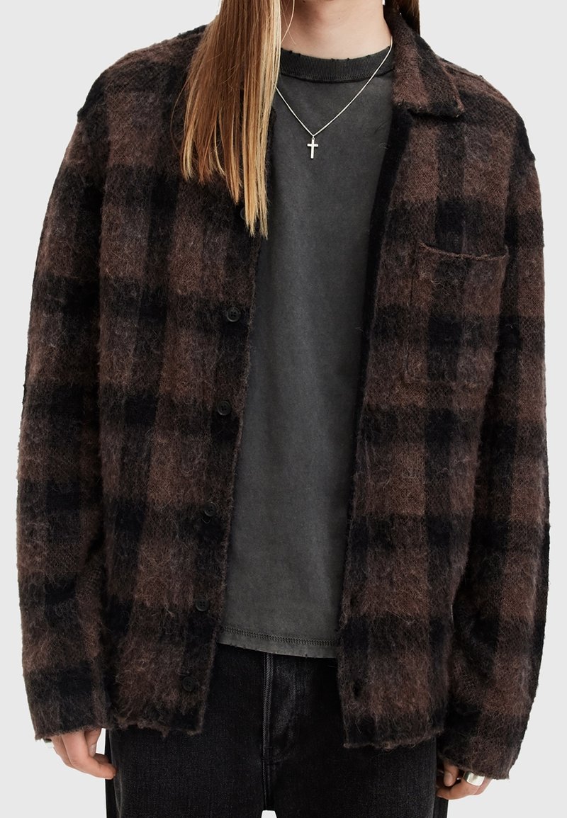 Brun och svart rutig button-up skjorta i mjukt material; har en bröstficka, stora knappar och avslappnad passform. Bärs över en grå skjorta.