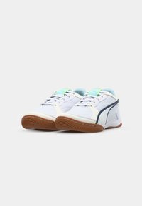White athletic shoes with a textured surface, featuring a light blue and green accent on the tongue and a brown rubber sole.