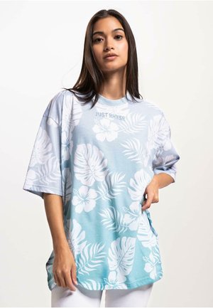 Korte mouwen, lichtblauw t-shirt met witte bloemen- en bladpatronen. Heeft een ronde halslijn en een ontspannen fit, merknaam op de borst.