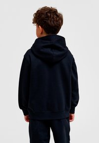 Svart luvtröja med avslappnad passform. Har ribbade muddar och fåll, mjuk tygtextur och en rymlig luva.