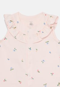 Rosa bomullsløs topp uten ermer med en volangkrage. Har små blomster mønstre i blått, rosa og grønt med knappefeste foran.