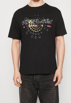 Camiseta negra de algodón con llamativos textos gráficos y patrones circulares en rosa y amarillo. Mangas cortas, corte relajado.