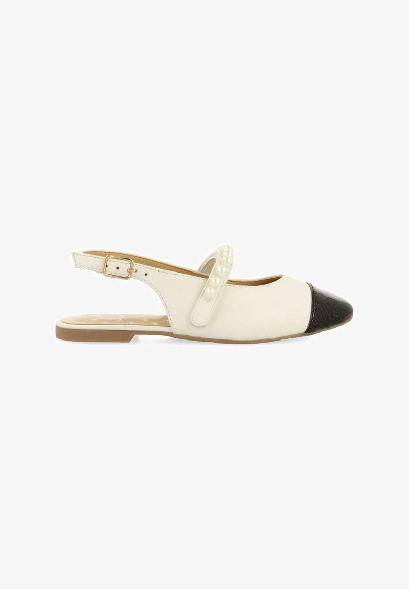 Zapato plano tipo slingback que presenta un cuerpo blanco, puntera negra, cuentas decorativas blancas en la correa y una suela marrón clara.