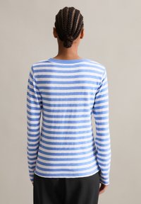 Koszula z długim rękawem w poziome niebiesko-białe paski. Wykonana z miękkiego materiału, z okrągłym dekoltem i luźnym krojem.