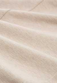 Tissu beige texturé avec un motif côtelé subtil, affichant de doux plis et une surface lisse, adapté à l'ameublement ou aux vêtements.