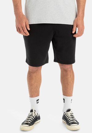 Black cotton shorts with a relaxed fit, finishing just above the knee, paired with white crew socks and black sneakers.