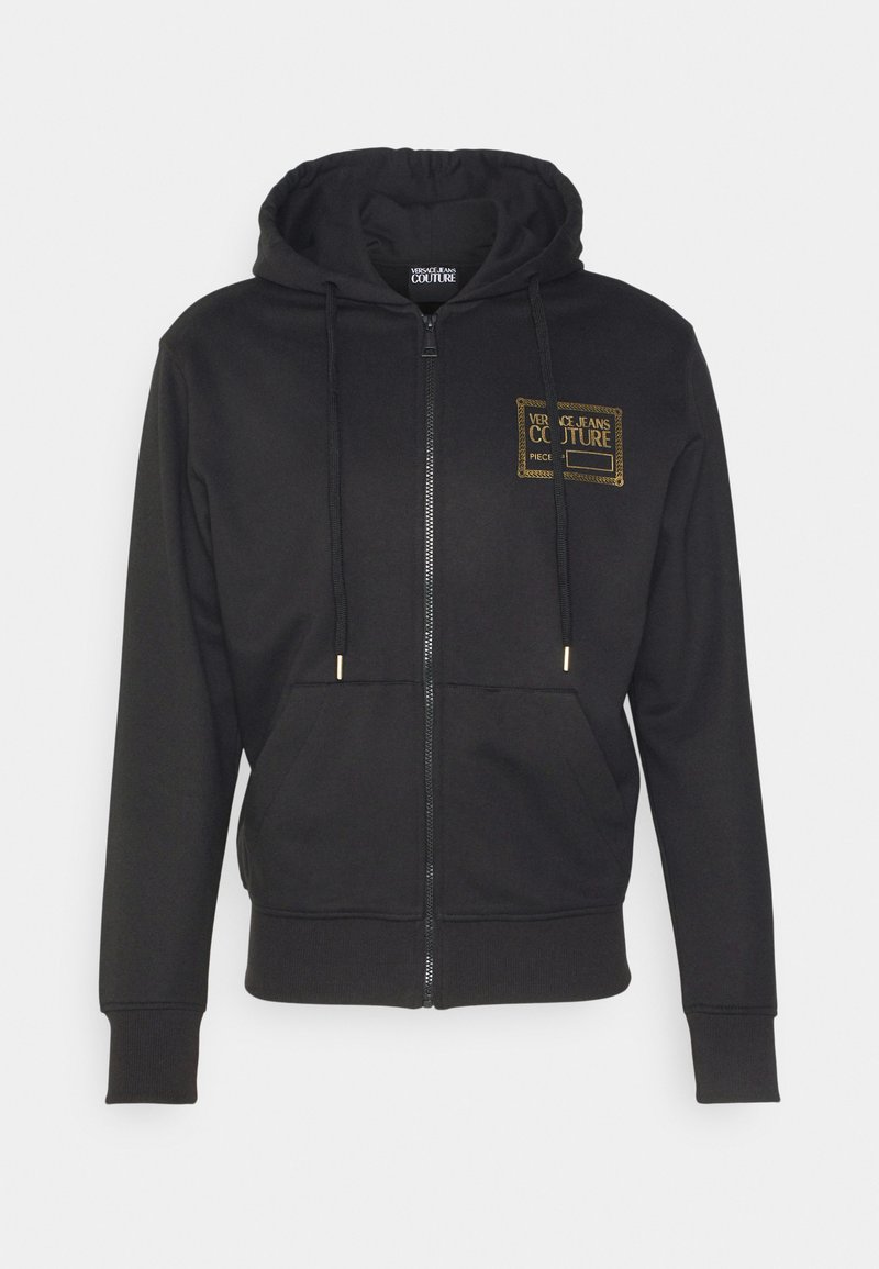 Zwarte zip-up hoodie van zachte stof. Beschikt over een capuchon met trekkoorden, zijzakken en een gouden logo print op de linker borst.