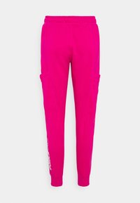 Pantaloni sportivi rosa con vita elasticizzata, gambe affusolate, tasche laterali e un logo stampato sulla gamba inférieure. Realizzati in tessuto morbido.