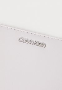 Calvin Klein lompakko pehmeästä vaaleanpunaisesta tekstuurimateriaalista, jossa on kohotettu hopeinen logo ja ommellut reunat kestävyydelle.
