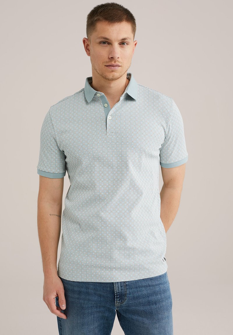 Polo cu mânecă scurtă, de culoare albastru deschis, cu un model geometric. Prezintă un guler și manșete în contrast, realizat dintr-o țesătură respirabilă.