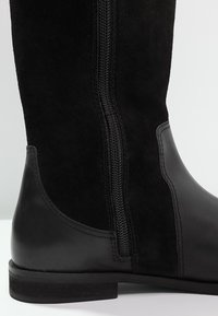 Stivali neri al ginocchio realizzati in una combinazione di suede e pelle, con un pannello in pelle liscia e una cerniera lungo il lato.