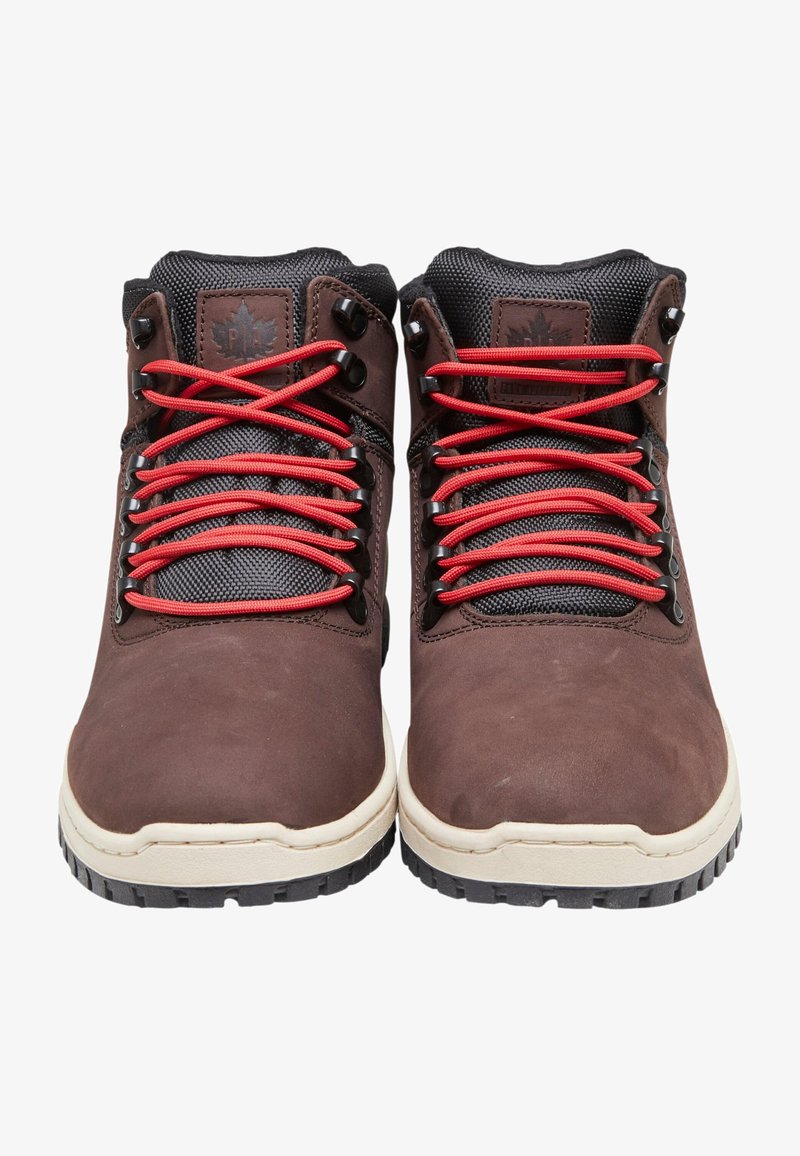 Pantofi din piele maro, cu vârf mediu, accentuați cu plasă neagră, șireturi roșii și o talpă din cauciuc crem; au ochiuri metalice și o etichetă cu logo.