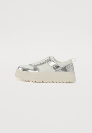 Białe sneakersy na platformie ze srebrnymi akcentami i teksturowaną podeszwą, widziane z boku na jednolitym tle.