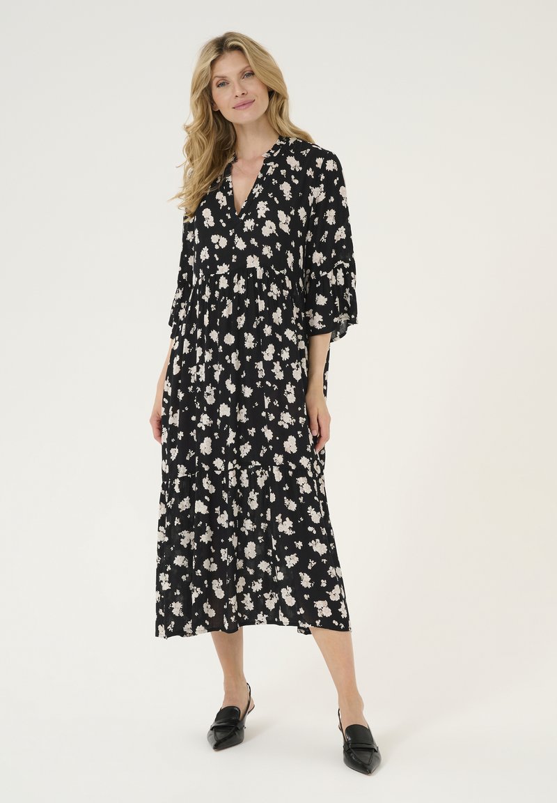 Robe noire à imprimé floral avec des manches trois-quarts, design à volants et tissu doux. Accentuée de fleurs blanches pour le contraste.