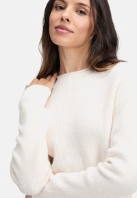 Jasna kremowa sweter z prążkowanej tkaniny, z długimi rękawami i okrągłym dekoltem, wykonany z miękkiej dzianiny dla wygodnego dopasowania.