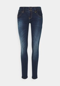 Pantalones vaqueros ajustados de un azul oscuro con un frente desgastado, cierre de doble botón y costuras y bolsillos con contraste amarillo.