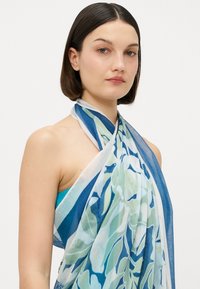 Bufanda ligera en tonos de azul y verde, con un patrón floral. Hecha de una tela suave y transparente con un diseño fluido.