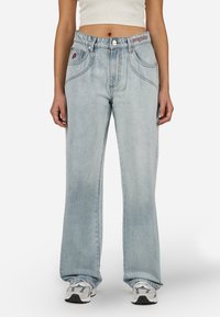 Világoskék farmerbő nadrág, enyhe kopással, öt zsebes stílusban és piros hímzett márkázással a derékrészen.