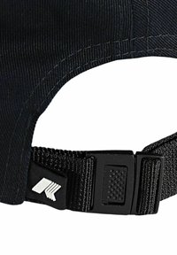 Casquette en tissu noir avec une sangle réglable et une boucle en plastique, ornée d'un petit logo géométrique blanc près de la fermeture.