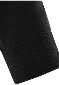 Nahaufnahme eines Ärmels aus schwarzem Strickstoff mit geripptem Bündchen und glattem Strick darüber, isoliert auf weißem Hintergrund.