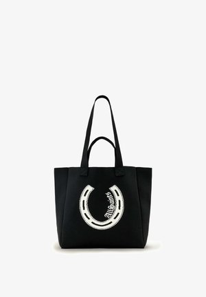 Sac fourre-tout en toile noire avec deux poignées et un grand graphisme blanc en forme de fer à cheval. Le design intègre le texte « AllSaints ».