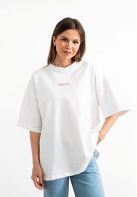 Biały, oversize'owy t-shirt wykonany z bawełny, z krótkimi rękawami i okrągłym dekoltem. Z przodu znajduje się różowy haft z napisem "MIRONS".